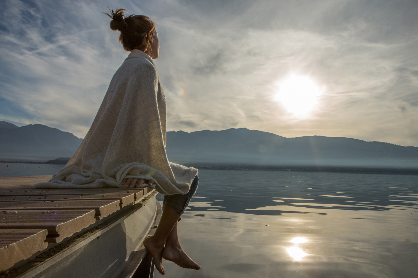 Frau sitzt an See und genießt Stille