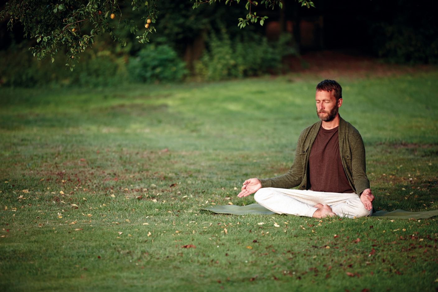 Mann meditiert auf einer Wiese