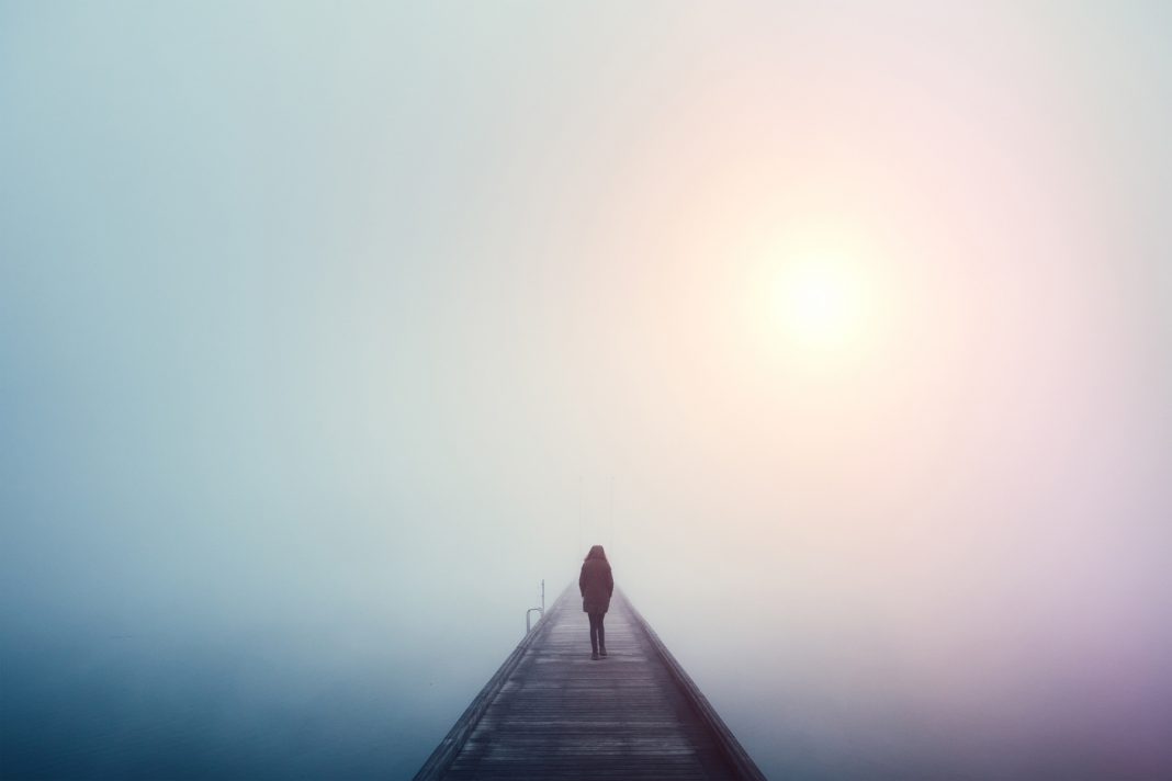 Frau geht über eine Brücke im Nebel